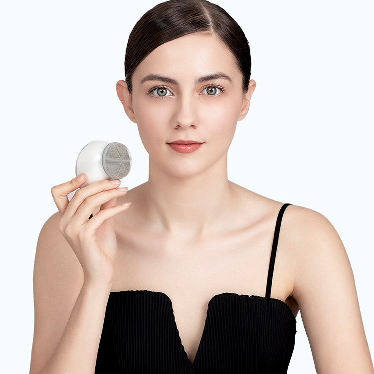 Woman using electric silicone facial cleansing brush in bathroom