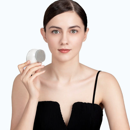 Woman using electric silicone facial cleansing brush in bathroom