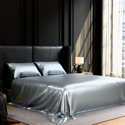 Bed with satin sheets and pillows in a modern bedroom setting.