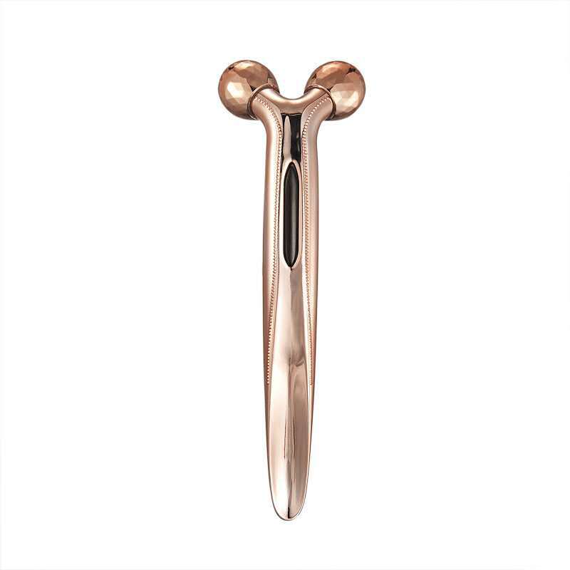 Rose gold facial massager on a white background