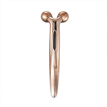 Rose gold facial massager on a white background